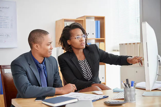 Entity Support and Management 2 black male female colleagues sitting office looking computer screen together 1098 20605 1